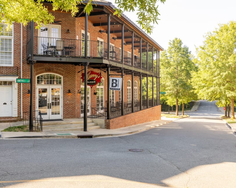 Exterior of Harvey's Bar & Grill, a brick building with a two-story balcony and outdoor seating.