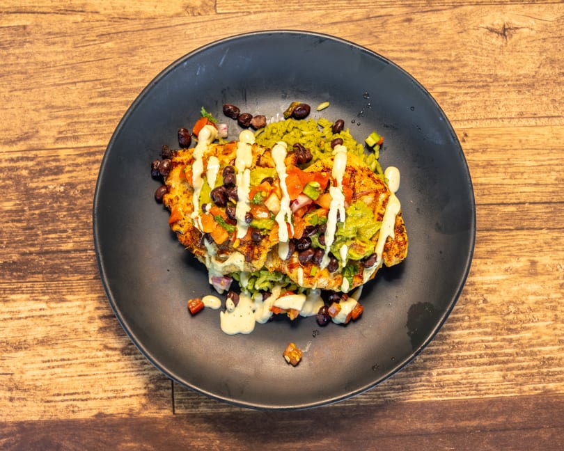 Grilled chicken topped with pico de gallo, black beans, guacamole, and a creamy sauce on green rice.