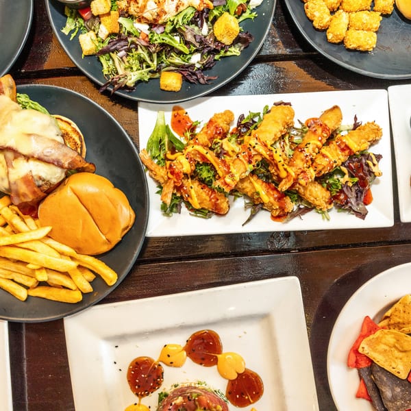 An overhead view of a table laden with various dishes, including a burger, fries, salads, and fried shrimp.